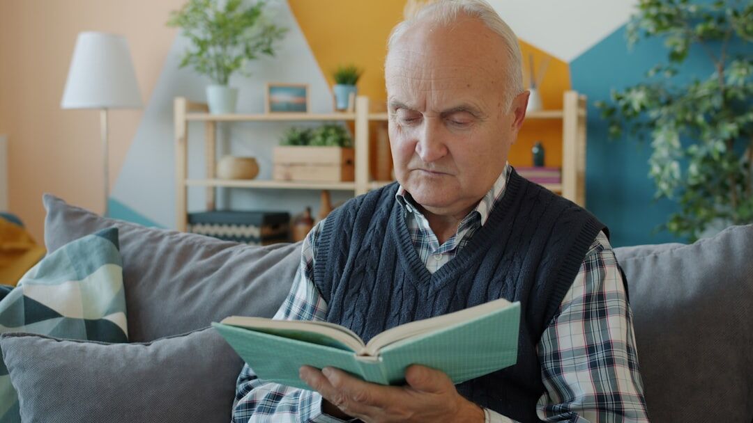 Elderly person writing notes in a notebook at home